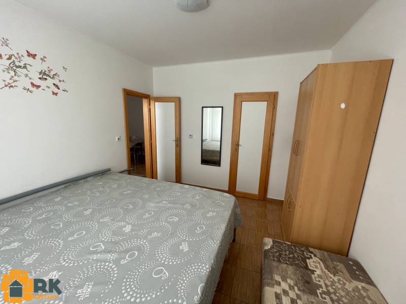 Ložnice s postelí, skříní a zrcadlem v rodinném domě s podlahou s dřevěným dekorem.