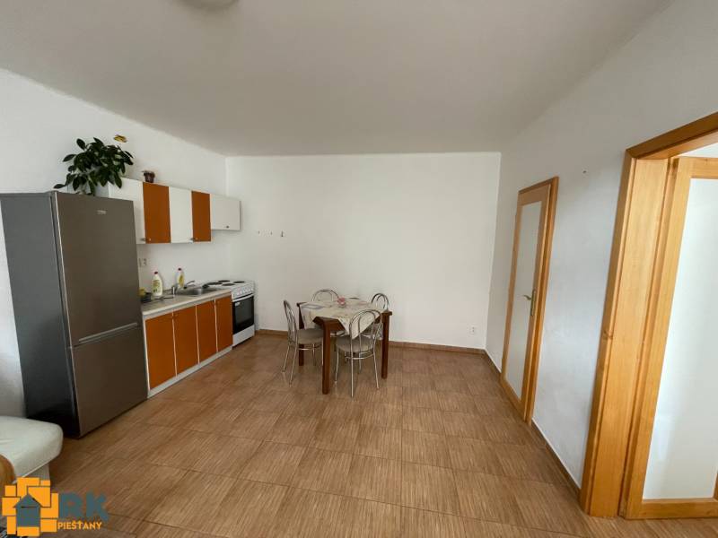 Kuchyně v rodinném domě s dlažbou a jídelním stolem.