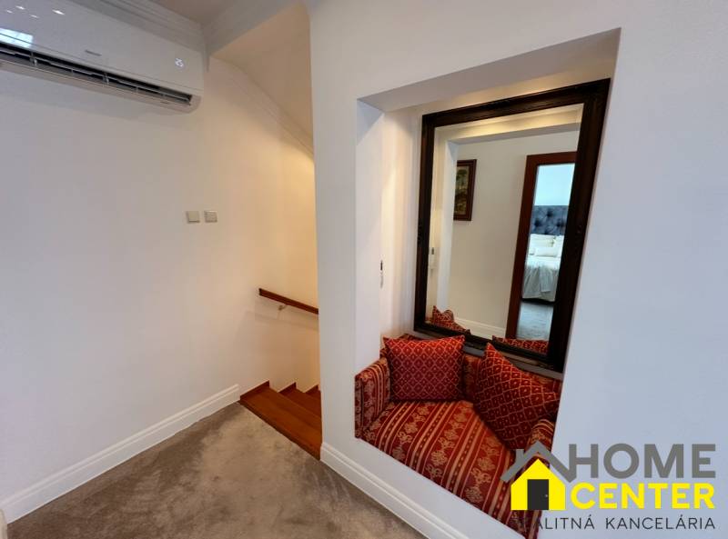 Rodinný dům zobrazuje schody s dřevěným dekorem, zrcadlo a sedací koutek s polštáři.