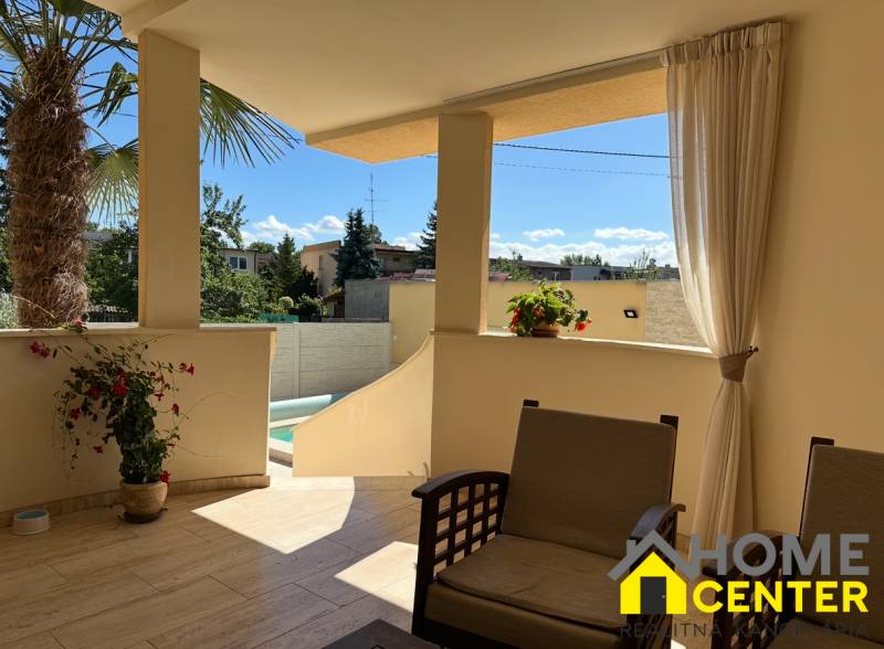 Terasa rodinného domu v Komárně s posezením a výhledem na dvůr s palmou.