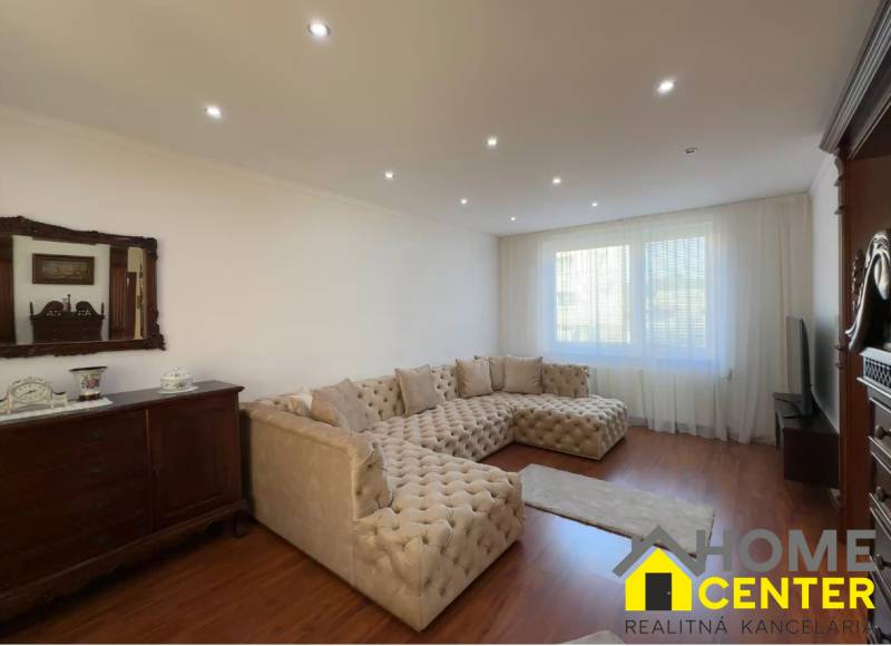 Obývací pokoj s velkou sedačkou, podlahou s dřevěným dekorem a starožitným nábytkem.