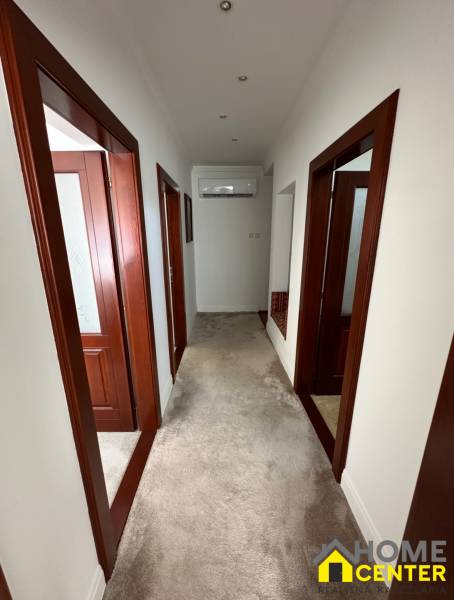 Chodba v rodinném domě s bílými stěnami, kobercem a dřevěnými zárubněmi.