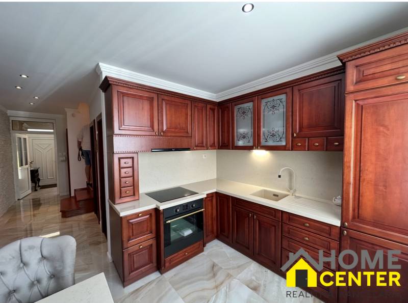 Kuchyně s tmavými dřevěnými skříňkami a podlahou s dřevěným dekorem v rodinném domě.