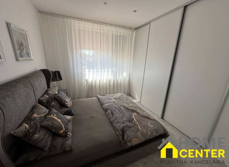 Ložnice v rodinném domě s tmavým ložním prádlem a velkou skříní.