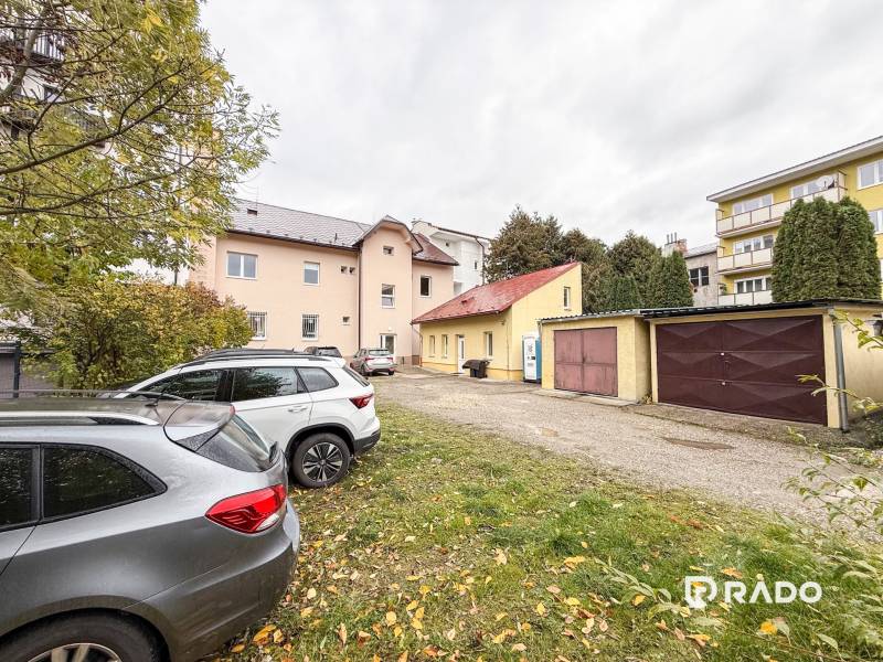 Parkoviště u kanceláří na Bratislavské ulici v Žilině, auta a garáže v pozadí.