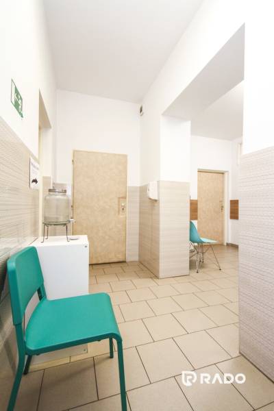 Čekárna v kancelářích s tyrkysovými židlemi a světlými stěnami.