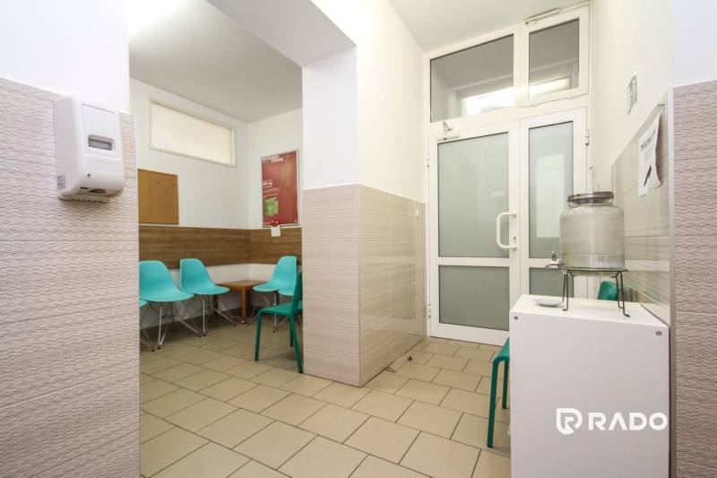 Čekárna v kanceláři s tyrkysovými židlemi a nádobou na vodu.