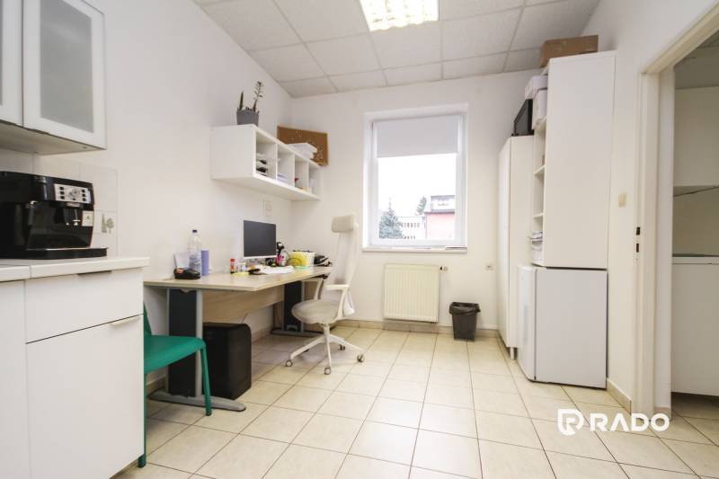 Kancelář s dlažbou, prostor s počítačem, nábytkem a kávovarem.