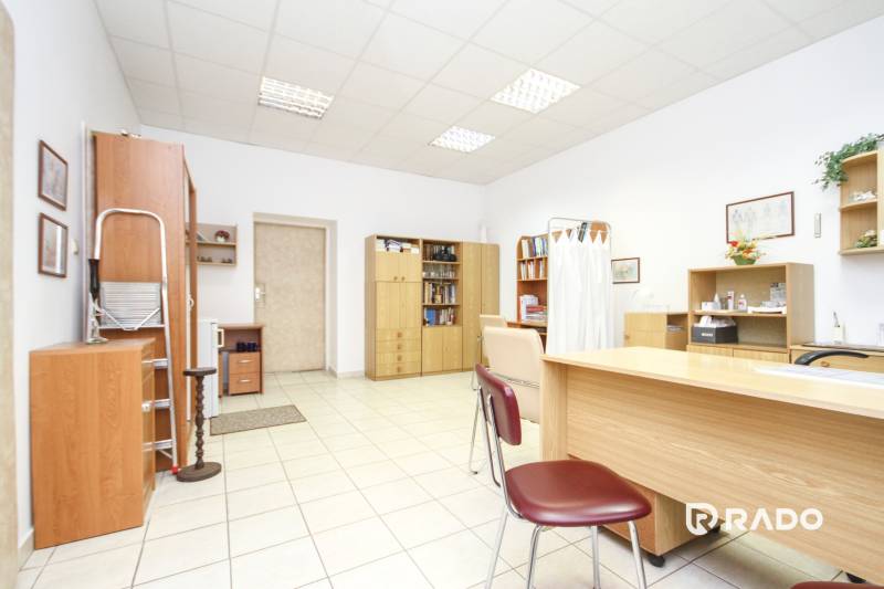 Kanceláře s bílými stěnami, dřevěným nábytkem a keramickou podlahou.