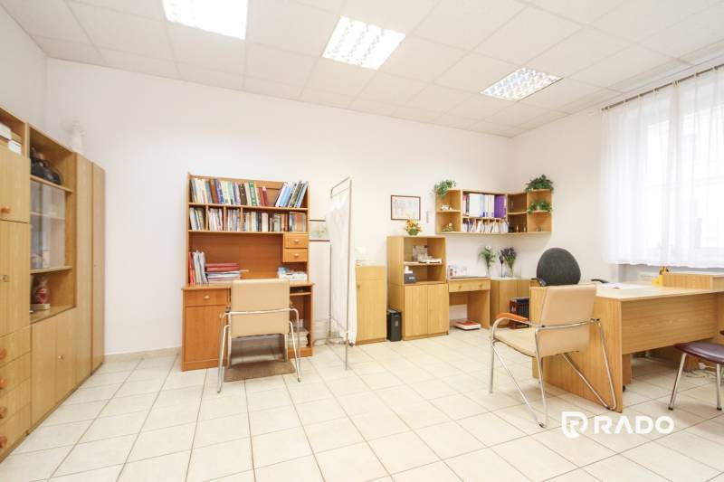 Kanceláře s nábytkem, židlemi a policemi na knihy, podlaha s keramickou dlažbou.