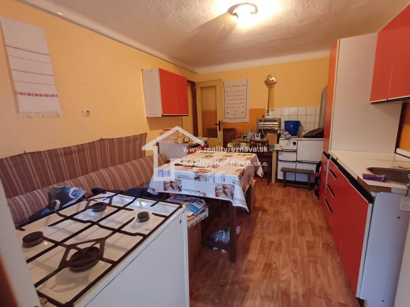 Kuchyně v rodinném domě s plynovým sporákem a podlahou s dřevěným dekorem.