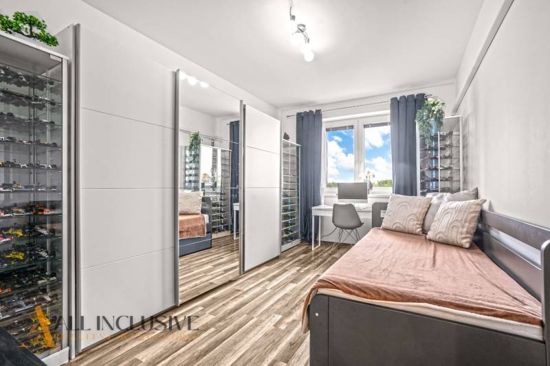 Pokoj se zrcadlovou skříní, pracovním stolem a podlahou s dřevěným dekorem ve 3pokojovém bytě.