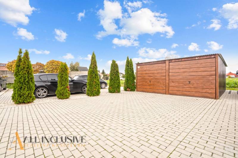 Parkoviště u 3pokojového bytu v Gabčíkovu, s auty a dřevěnou garáží.