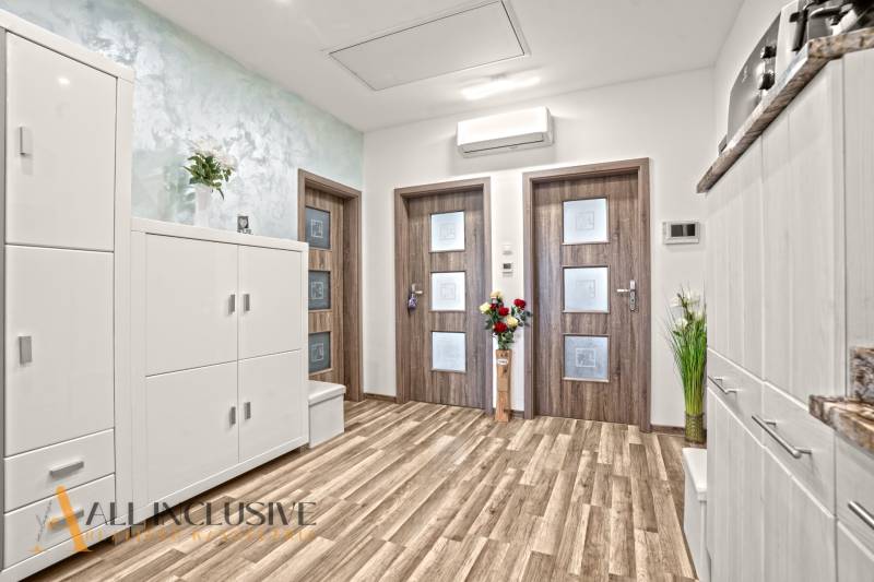 Interiér 3-pokojového bytu s podlahou s dřevěným dekorem a bílým nábytkem.