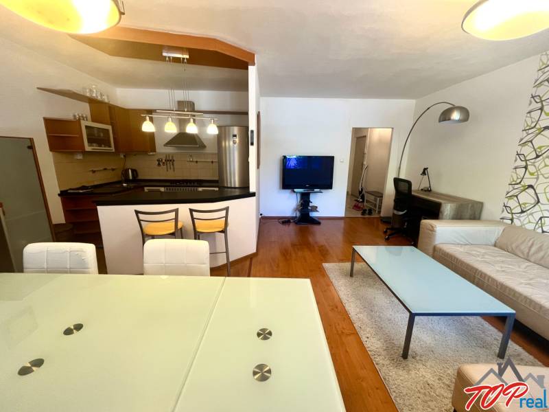 Obývací pokoj v 3pokojovém bytě s kuchyní, jídelním stolem a pohodlným sezením.