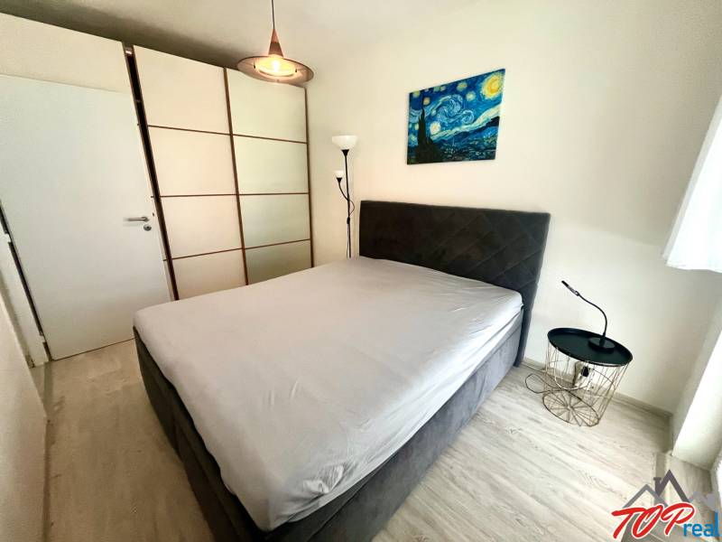 Ložnice v 3-pokojovém bytě s šatní skříní a nočním stolkem.