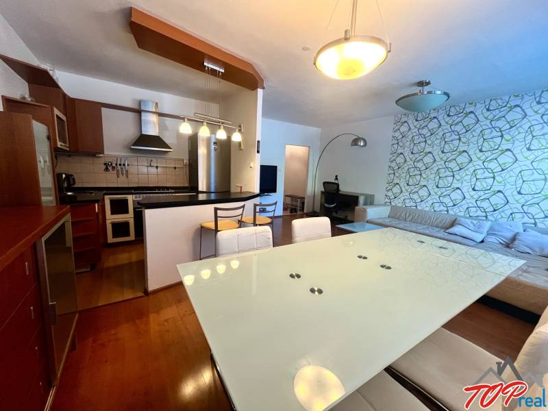 Kuchyně a obývací pokoj v 3pokojovém bytě s moderním nábytkem a dekorativní stěnou.