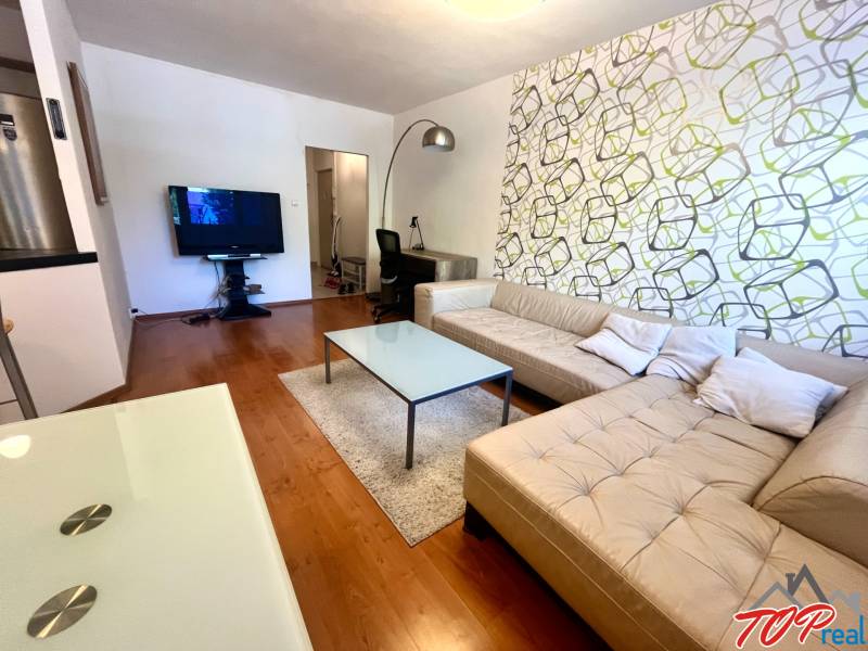 Obývací pokoj s béžovou sedačkou a televizorem v 3pokojovém bytě.