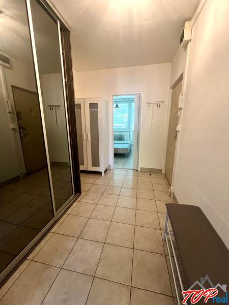 Vstupní chodba s dlažbou v 3-pokojovém bytě, šatní skříň a botník.