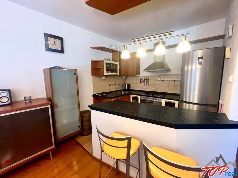 Kuchyně v 3pokojovém bytě s barovým pultem, kovovými židlemi a elegantními lampami.