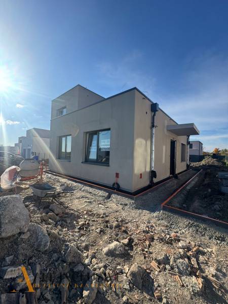 Rodinný dům v Hubicích ve výstavbě s neupraveným terénem. Jasná obloha a sluneční světlo.