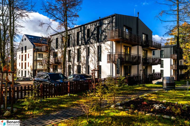 Exteriér bytového domu na Lúčnej ulici v Štrbě s zaparkovanými vozidly a upraveným okolím.