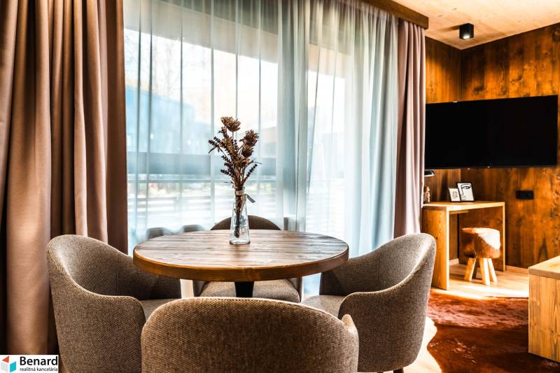 Jídelní kout ve 2-pokojovém bytě s podlahou s dřevěným dekorem a výhledem z okna.