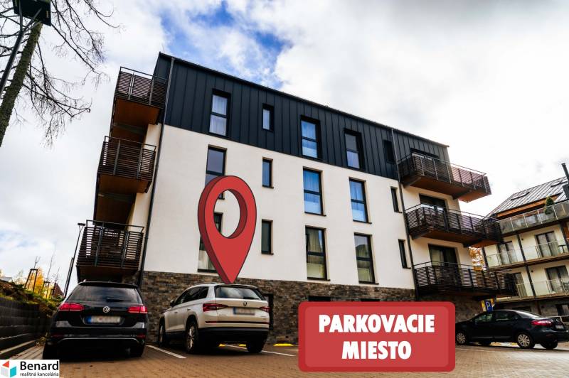 Bytový dům na Lúčnej ulici ve Štrbě s vyznačeným parkovacím místem v popředí.