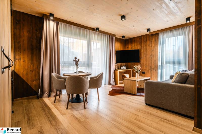 Obývací pokoj v 2-pokojovém bytě s podlahou s dřevěným dekorem, sedačkou a jídelním stolem.