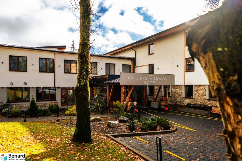 Budova hotelu se stromy a padajícím listím ve Štrbě na ulici Lúčna.