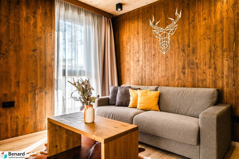 Obývací pokoj v 2pokojovém bytě s podlahou s dřevěným dekorem a dekorací na stěně.