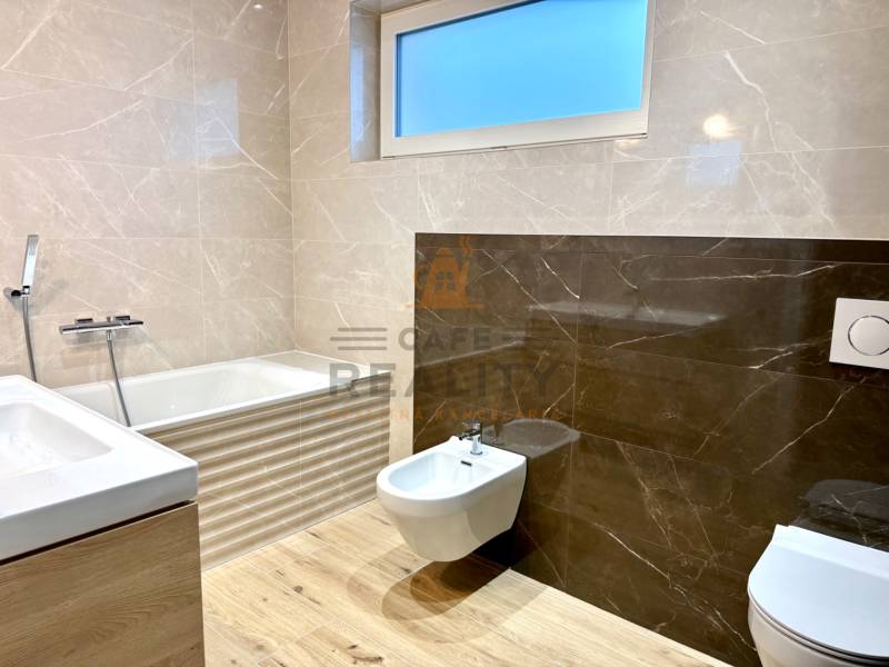 Koupelna v rodinném domě s vanou, umyvadlem, bidetem a podlahou s dřevěným dekorem.