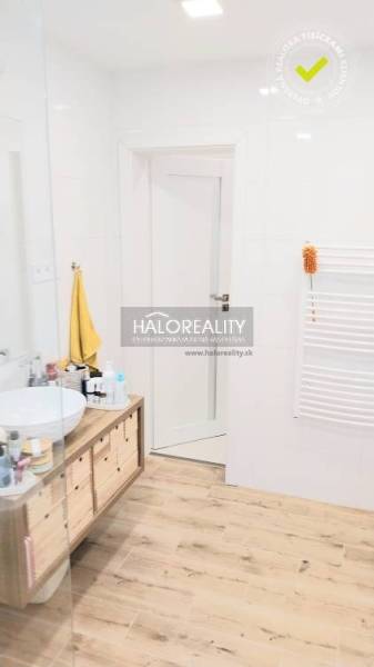 Koupelna s podlahou s dřevěným dekorem, umyvadlem na desce a bílými stěnami v 3-pokojovém bytě.