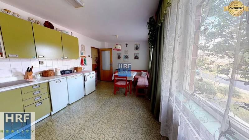 Kuchyně v rodinném domě s retro nábytkem, stolem, velkým oknem a dekoracemi.