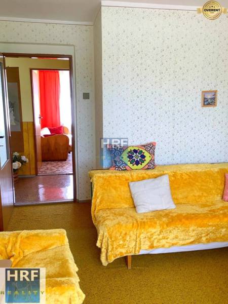 Obývací pokoj v rodinném domě s barevnými dekami a polstrováním na sedačkách.