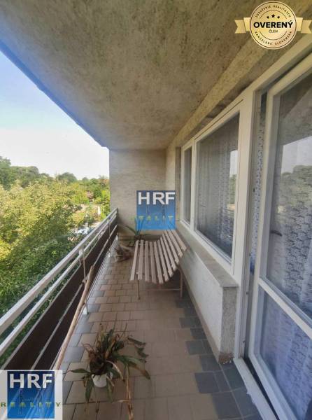 Balkon rodinného domu s dřevěnou lavicí, rostlinou a výhledem na zahradu v Radošovicích.