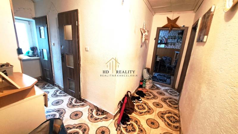 Chodba v 2-pokojovém bytě s dekorativní dlažbou a nábytkem.