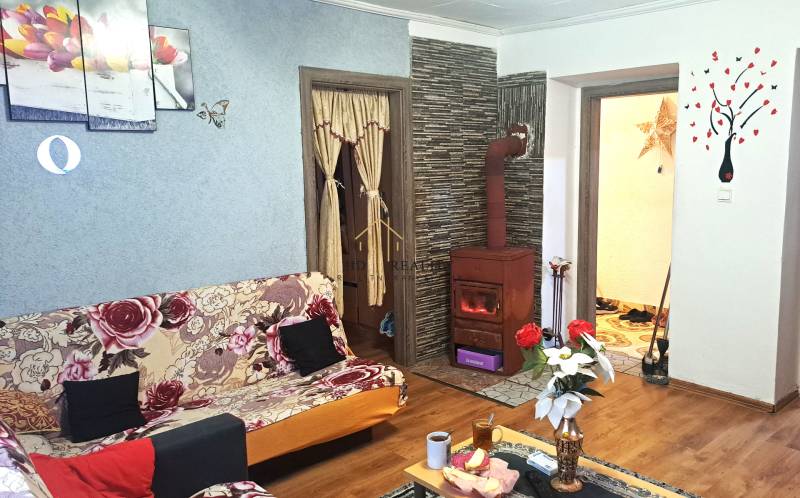 Obývací pokoj v 2-pokojovém bytě s kachlovými kamny a podlahou s dřevěným dekorem.