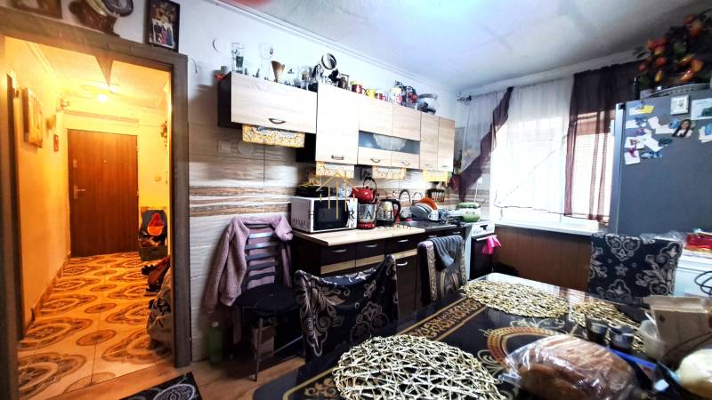 Kuchyně v 2-pokojovém bytě se světlou podlahou s dřevěným dekorem a bohatým zařízením.