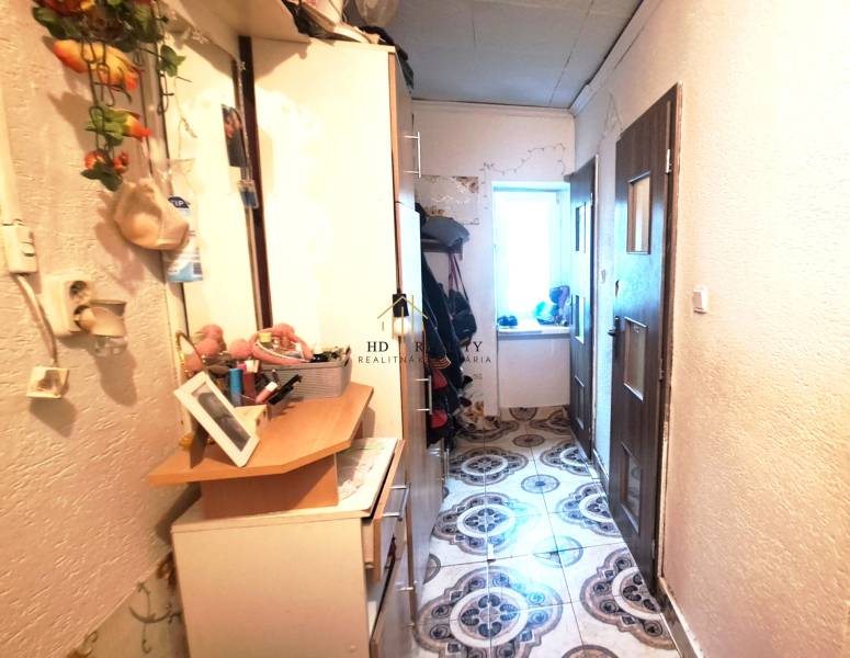 Chodba s skříňkami a dekoracemi v 2-pokojovém bytě. Vlevo věšáky, vpravo dveře.