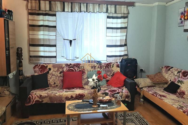 Obývací pokoj v 2pokojovém bytě se vzorovanými pohovkami a podlahou s dřevěným dekorem.