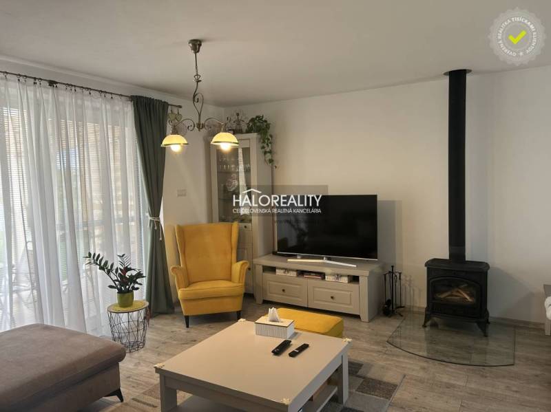 Obývací pokoj v rodinném domě s krbem, žlutým křeslem a televizorem.