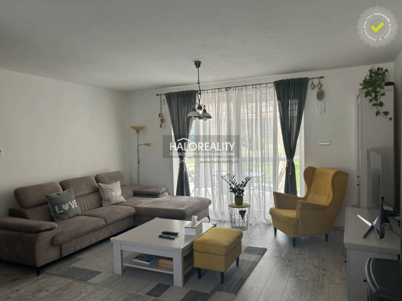 Obývací pokoj v rodinném domě s pohodlnou sedačkou a žlutým křeslem.