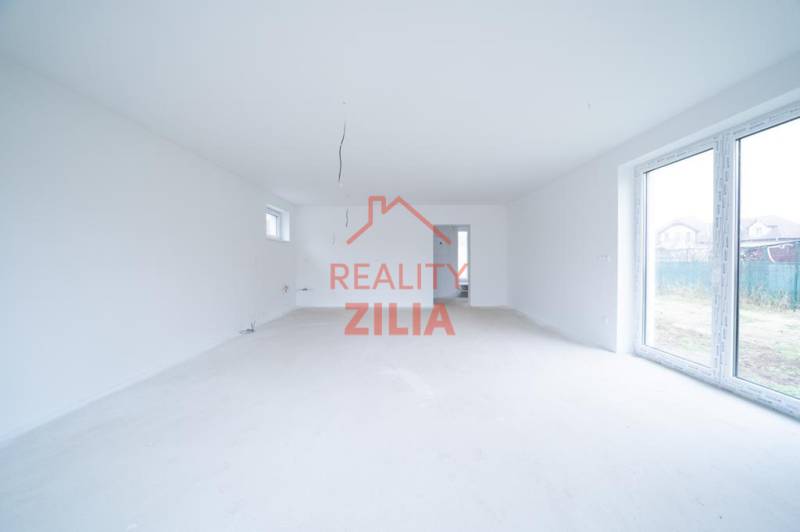 Prostorná světlá místnost v rodinném domě s velkými okny.