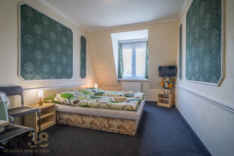 Pokoj s manželskou postelí, kobercovou podlahou, televizorem, židlí a dekoracemi v hotelech a penzionech.