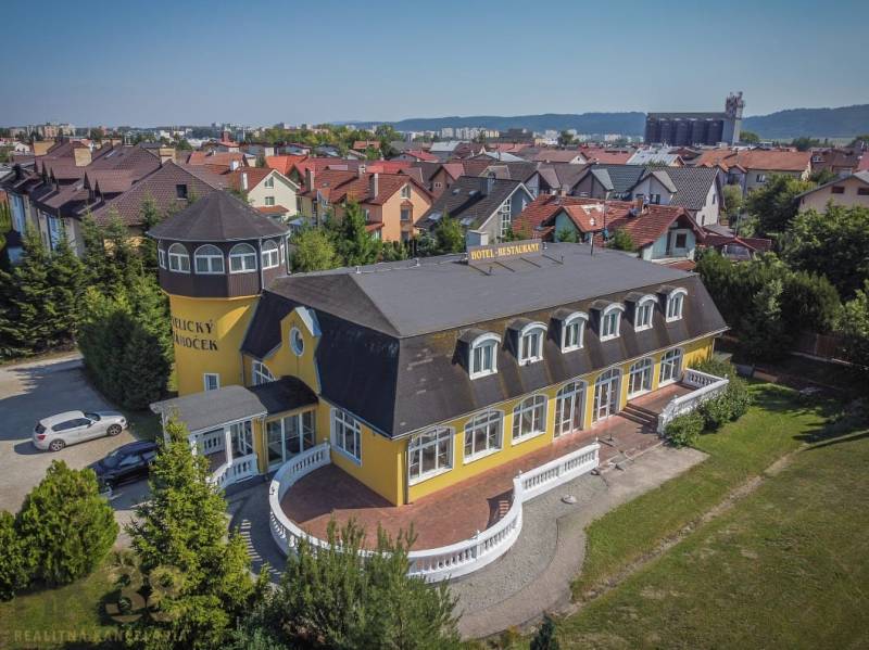 Žlutý hotel s věží, obklopený zahradou ve městě Poprad, hotely a penziony.