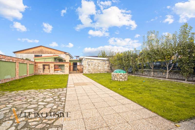 Zahrada u rodinného domu na Kúpeľnej ulici v Dunajskej Stredě s trávníkem a dlažbou.