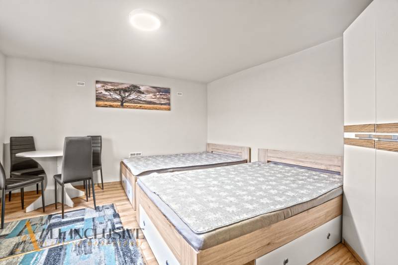 Ložnice v rodinném domě s dvěma postelemi, skříní a podlahou s dřevěným dekorem.