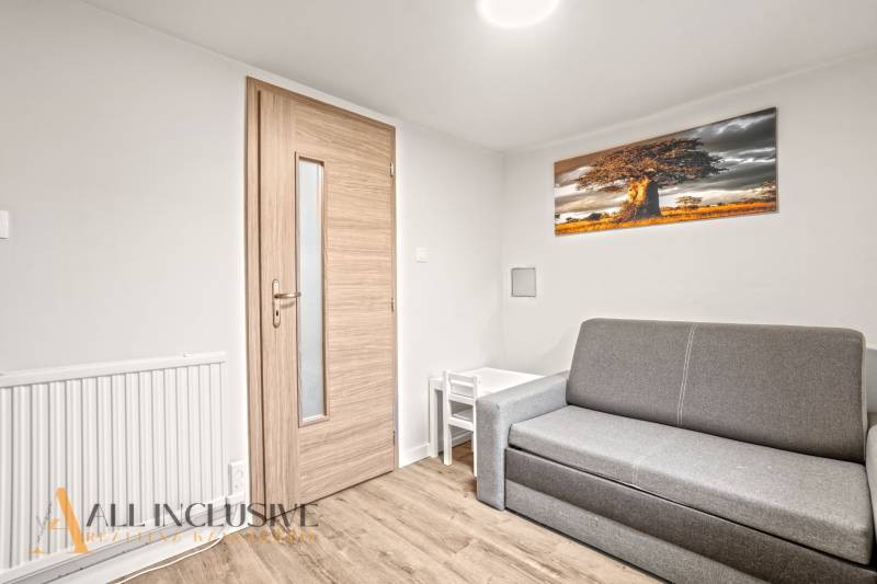 Obývací pokoj v rodinném domě s pohovkou, stolkem a podlahou s dřevěným dekorem.