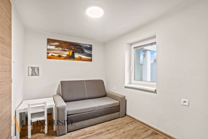 Pokoj rodinného domu s pohovkou, obrazem stromu a podlahou s dřevěným dekorem.